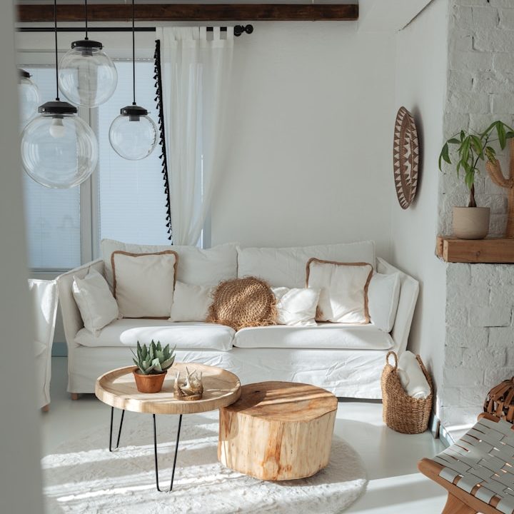 Helles Wohnzimmer mit beigem Sofa, runden Tischen und Grünen Pflanzen.